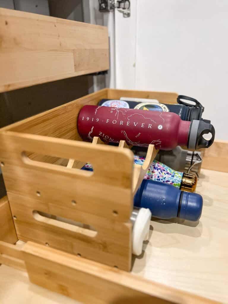 A side view of water bottles arranged inside a wooden wine rack