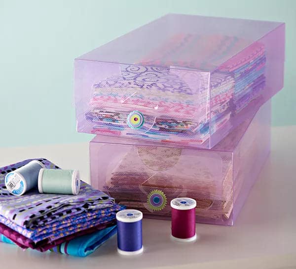 A view of fabrics store inside purple transparent photo boxes with purple threads on the side