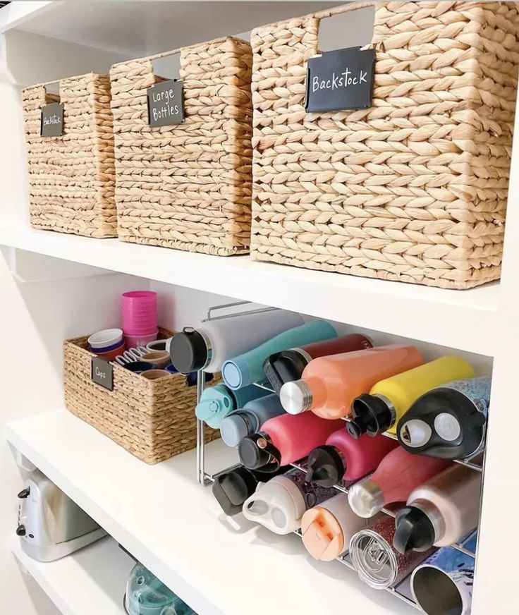 A view of water bottles stored under a cabinet with jute boxes on top