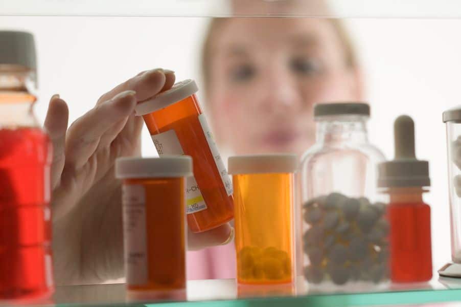 a woman sorting pills from a cabinet