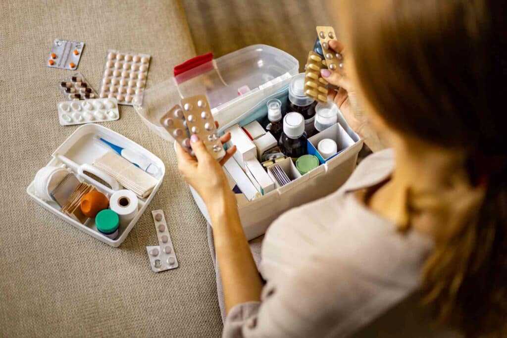 a woman sorting pills from a stackable box rest of medicines placed on ground