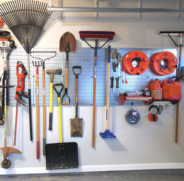 gardening tools set up in the pegboard from cans and hoses to pruning shears and racks