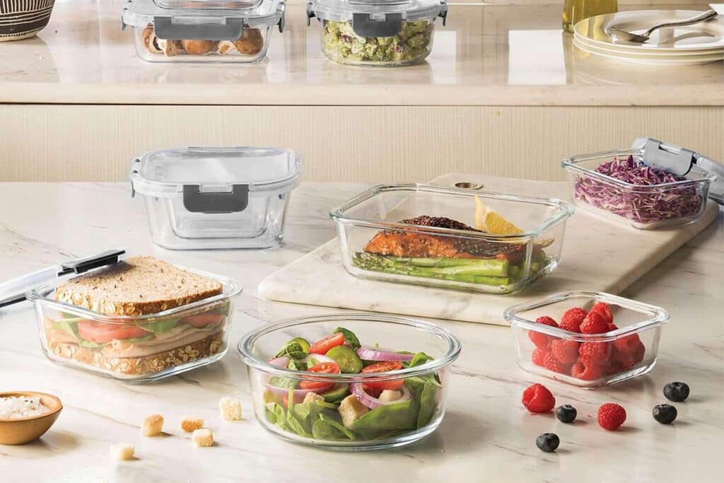 A view of salads and sandwiches inside glass containers on a kitchen counter