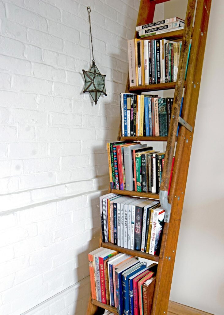 books organized in a ladder placed in the corner