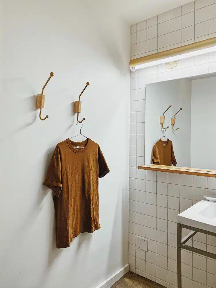 A view of clothing hung on wall hooks inside a dorm vertical space jpg