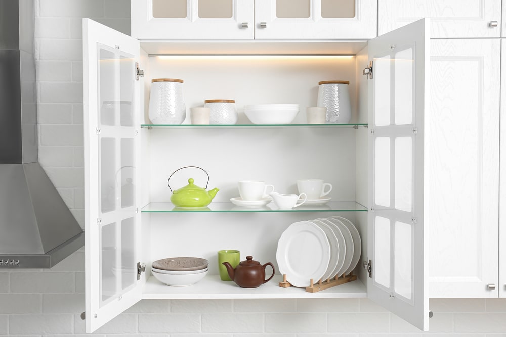 A view of an open cabinet shelf with kitchen utensils